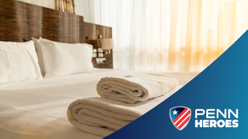 hotel bed with towels and PENN Hero logo in corner